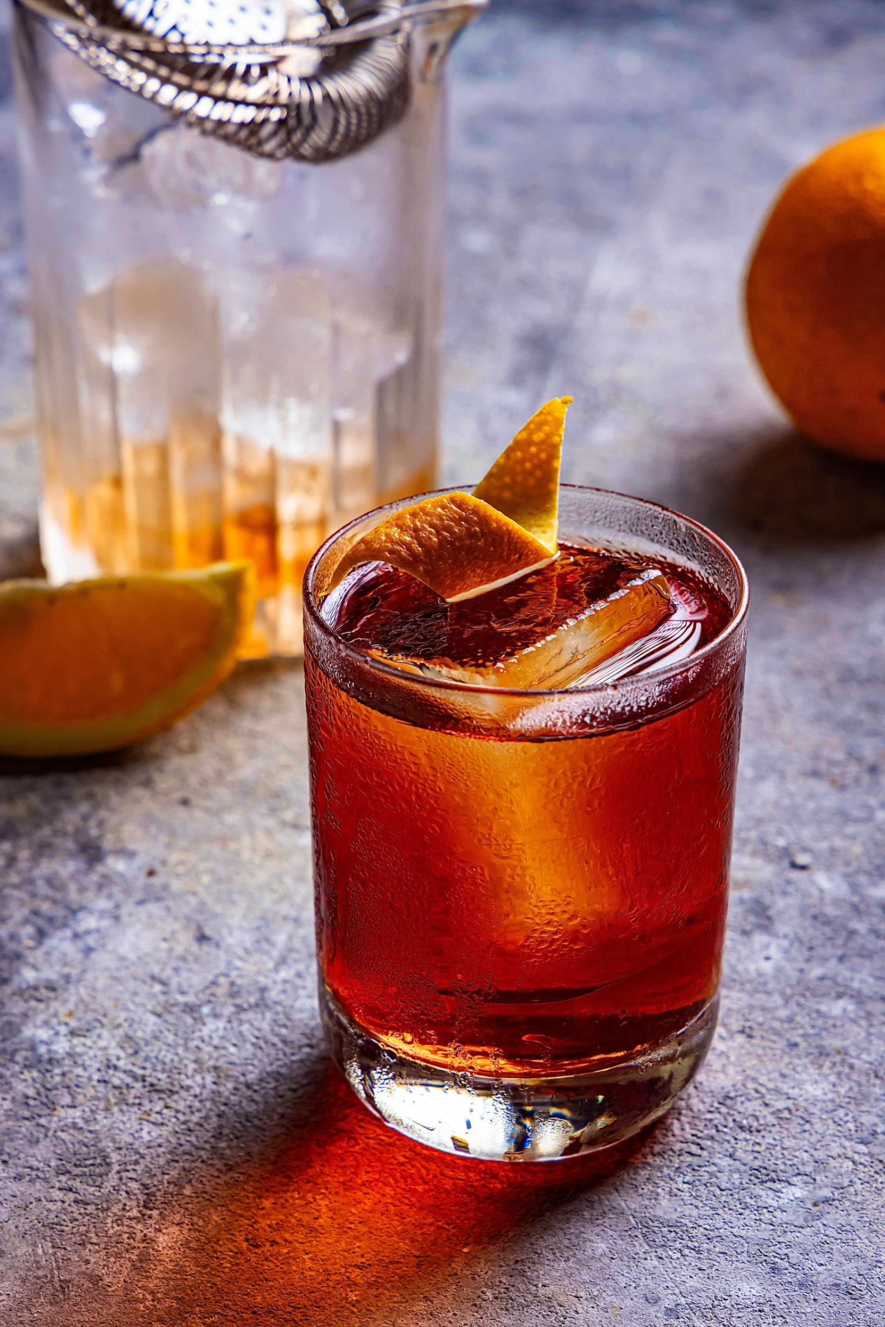 Coquetel vermelho âmbar com casca de laranja em copo baixo
