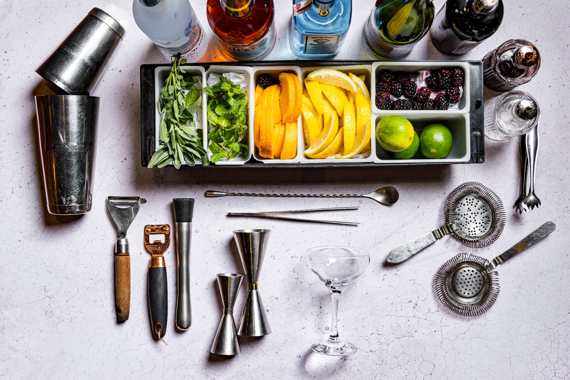 Mise en place de bar com utensílios, garrafas, ervas e cítricos vista de cima